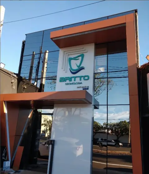 Fachada em ACM cobre com totem branco da Britto Odontologia em frente a vidros espelhados