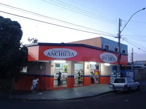 Fachada em ACM vermelho com letreiros ovais da Casa de Carnes Anchieta, em fim de tarde