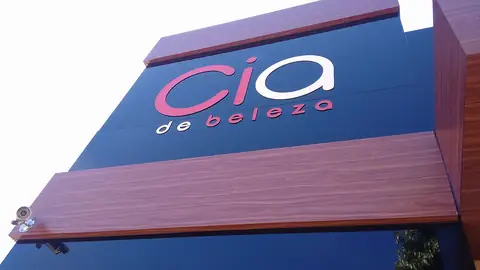 Painel em ACM azul-marinho e faixas amadeiradas com letras vazadas da Cia de Beleza