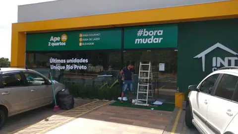 Fachada de stand de vendas com moldura em ACM amarelo e painel verde com texto branco