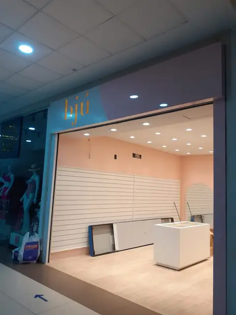 Interior de loja em obra com sanca em ACM e nome em letras no alto, parede com painel ripado