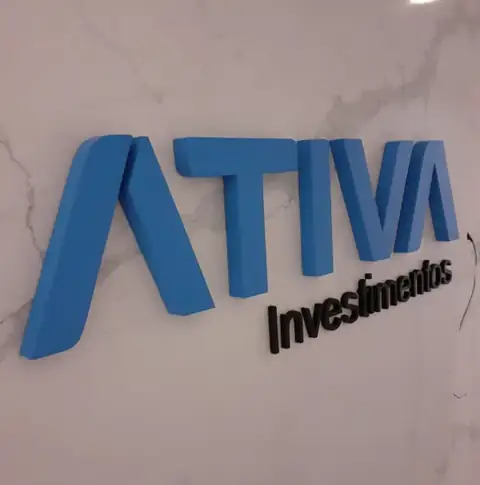 Letras caixa azuis e pretas da Ativa Investimentos sobre parede de mármore rosado
