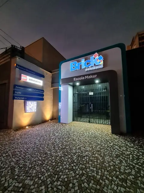Pórtico em ACM da Brick Solutions à noite, com letras iluminadas e piso de pedras