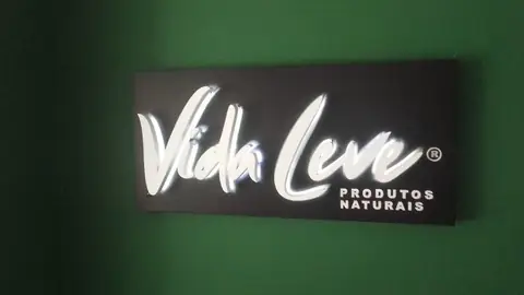 Painel preto com letras brancas retroiluminadas da Vida Leve Produtos Naturais em parede verde