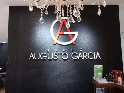 Logo e letras caixa brancas do Grupo Augusto Garcia sobre painel preto com lustre de cristal