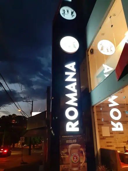 Totem vertical iluminado com letras brancas da Romana ao entardecer