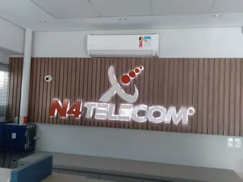 Letras caixa iluminadas com logo da N4 Telecom sobre painel ripado de madeira na recepção