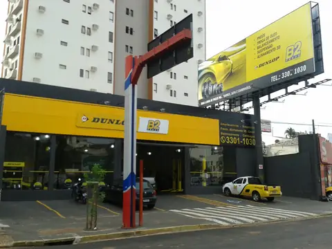 Fachada amarela e outdoor lateral impresso de loja de pneus Dunlop, em avenida