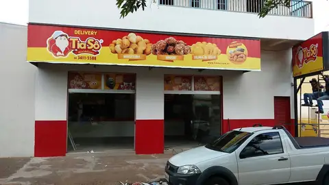 Fachada de delivery com faixa impressa vermelha e amarela da Tia Sô com salgados