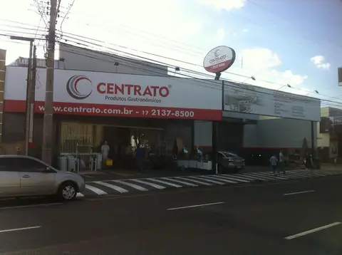 Fachada com faixa branca e vermelha impressa da Centrato, produtos gastronômicos, e placa redonda