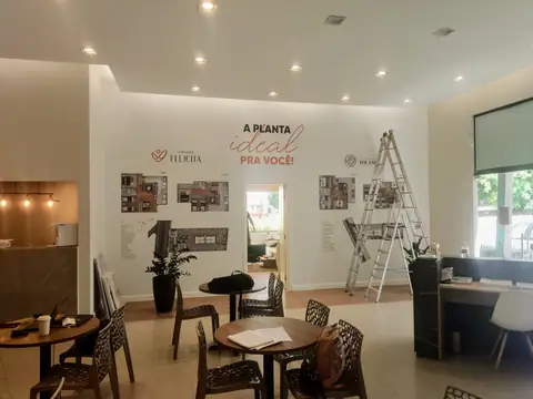 Stand de vendas interno com adesivos de parede 'A planta ideal pra você' e mesas de reunião