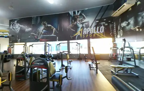 Painel impresso de atletas em parede de academia da Apollo Sports, acima dos aparelhos