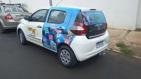 Carro branco com envelopamento parcial da Fast Net Telecom, traseira azul com ícones de apps