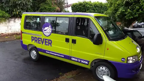 Van verde-limão com faixas roxas e logotipo Prever, vista em ângulo de três quartos