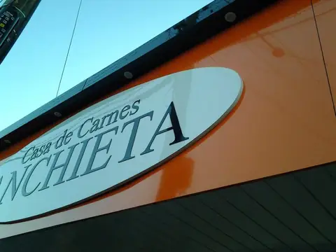Placa oval branca em relevo sobre ACM laranja da Casa de Carnes Anchieta, vista de baixo