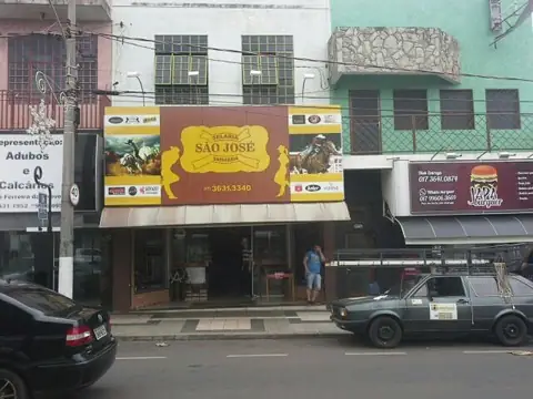 Fachada de padaria com painel marrom e dourado São José e fotos de cavalos, rua com carros