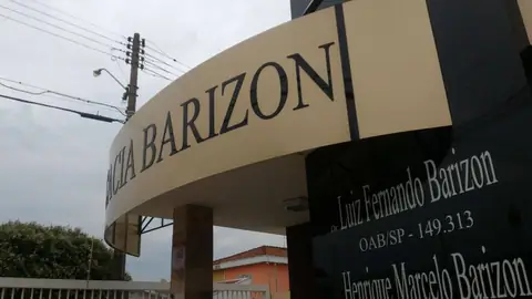 Marquise curva em ACM bege com letras pretas Barizon e placa preta com nomes de advogados