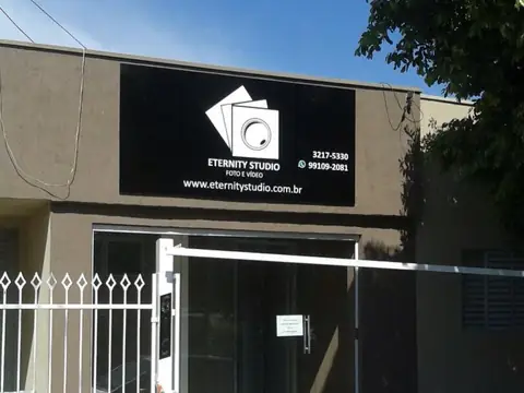 Painel preto com logotipo branco da Eternity Studio, foto e vídeo, sobre fachada cinza