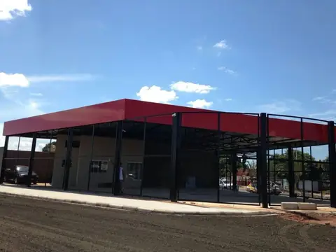 Cobertura em ACM vermelho sobre estrutura metálica de loja térrea ainda em obra, céu azul