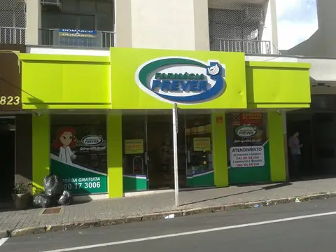Fachada verde-limão em ACM com logotipo oval Farmácia Prever e adesivos nas vidraças