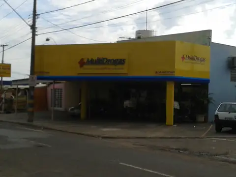 Fachada em ACM amarelo com letreiro MultiDrogas e faixa azul, vista da rua