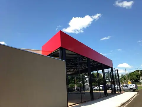 Cobertura em ACM vermelho de estrutura metálica e muro bege, céu azul com nuvens