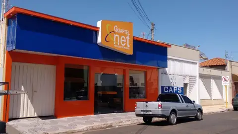 Fachada em ACM azul e laranja com letreiro Guaptel net, picape prata estacionada