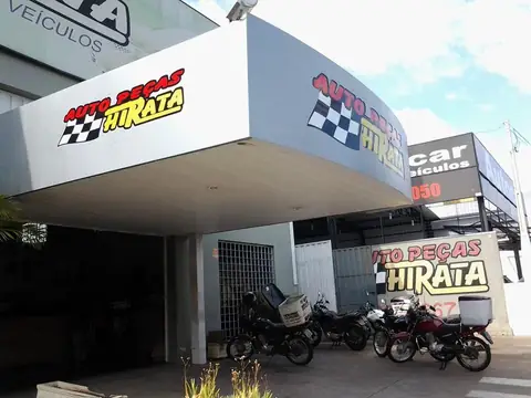 Marquise curva em ACM cinza com letras Auto Peças Hirata e motos estacionadas