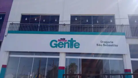 Fachada branca com letreiro verde-água Gente Rede Farma e Drogaria São Sebastião