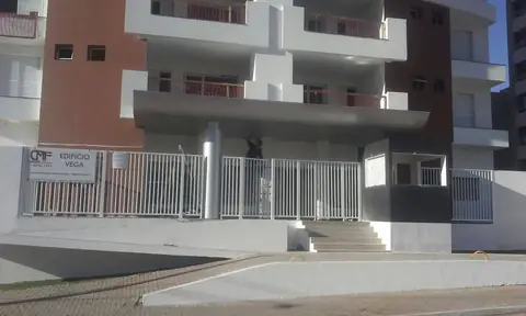 Fachada do Edifício Vega com marquise em ACM cinza e gradil branco, escada de entrada