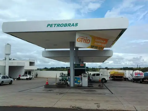 Posto de combustível Petrobras com grande cobertura branca e letras verdes, sob céu nublado