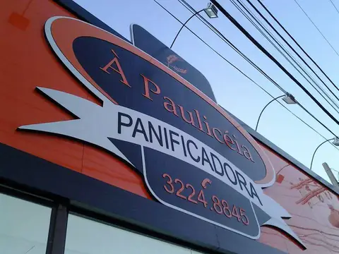 Fachada em ACM laranja com painel da À Paulicéia Panificadora, vista de baixo