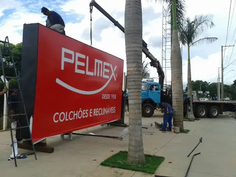 Painel vermelho da Pelmex Colchões e Reclináveis sendo instalado com guindaste