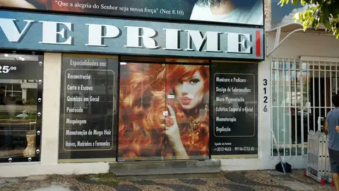 Vitrine de salão de beleza com adesivo de rosto feminino e lista de serviços em vinil