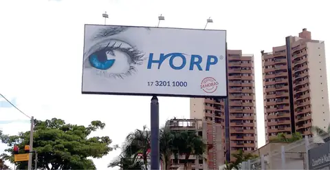Outdoor da Horp com olho azul em destaque, instalado em poste diante de prédios