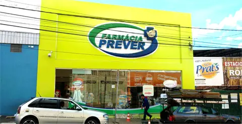Fachada amarelo-limão da Farmácia Prever com letreiro oval verde na platibanda