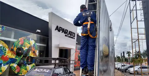 Instalador com cinto de segurança fixando painel ao lado da fachada da Aparato Interiores