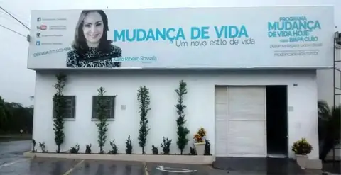 Fachada branca com faixa de lona impressa em azul do Ministério Mudança de Vida e foto de mulher