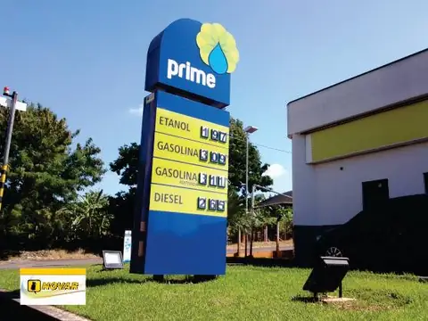 Totem azul do posto Prime com preços de combustíveis em painel, gramado ao redor