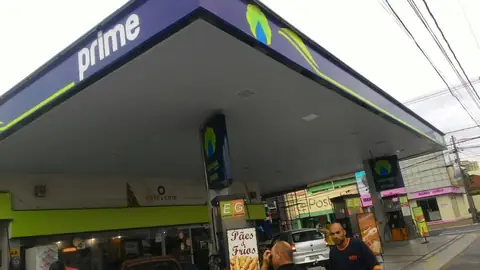 Cobertura azul e verde do posto Prime vista por baixo, com totem ao fundo
