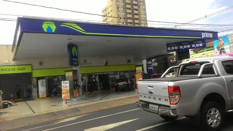Posto Prime com cobertura azul e faixa verde-limão, picape cinza em primeiro plano