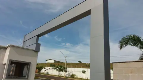 Detalhe de pórtico em ACM cinza claro visto de baixo, com guarita à esquerda