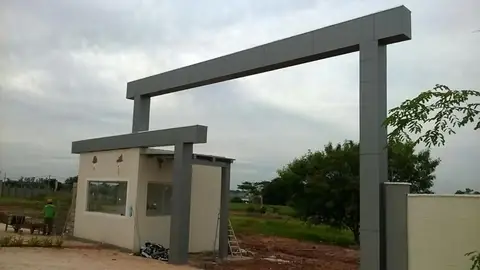 Pórtico em ACM cinza escuro sobre guarita bege, em obra de condomínio