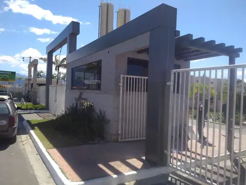 Guarita revestida em pedra com pórtico e pergolado em ACM cinza, portão gradeado
