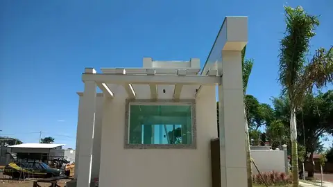 Guarita bege com pergolado branco e vidro verde, ACM claro, céu azul