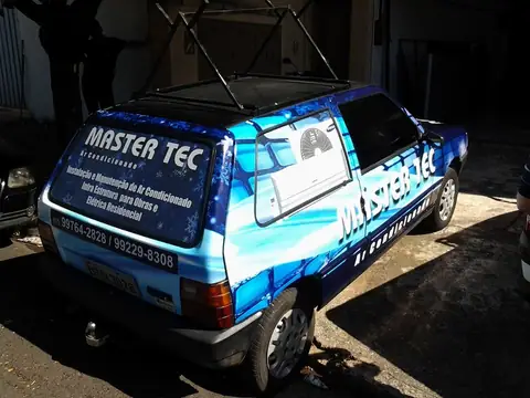 Uno azul envelopado com a arte da Master Tec Ar Condicionado e telefones no vidro traseiro