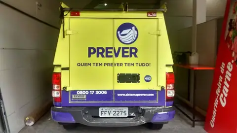 Traseira de utilitário amarelo-limão e roxo da Prever com slogan e telefone