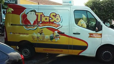 Van branca envelopada em vermelho e amarelo com mascote e logo da Tia Sô Minidelícias