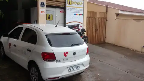 Gol branco com logo da Incor aplicado na lateral, estacionado em frente a uma loja