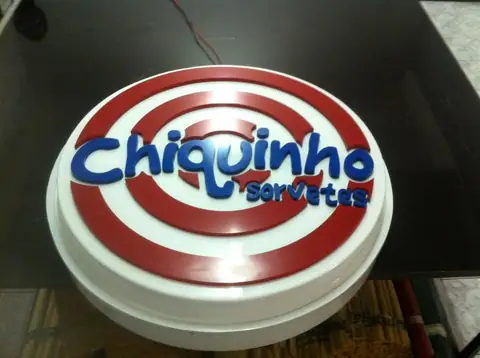 Luminoso redondo com anéis vermelhos e logo em relevo Chiquinho Sorvetes, visto de cima